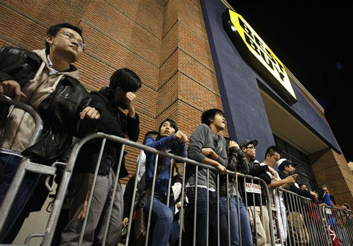 Shoppers stand in line outside a Best Buy...