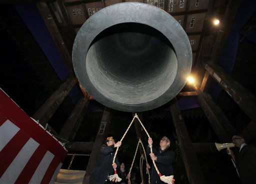 Worshipers strike a giant bell to celebrate the...