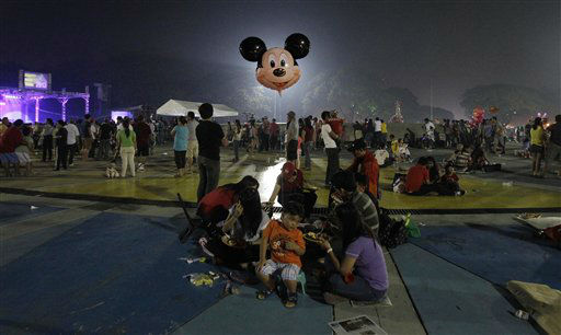 A Filipino boy holds a Mickey Mouse balloon as...