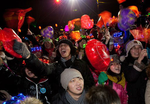 Chinese people wave national flags as they...