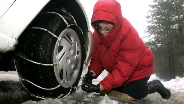 Woman places chains on tires in preparation of winter weather